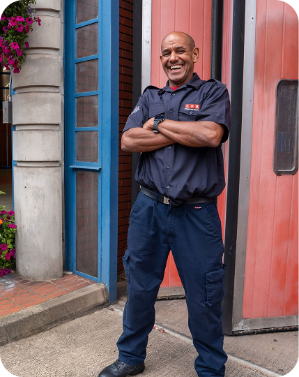 Uniformed worker stands confidently in doorway with arms crossed.